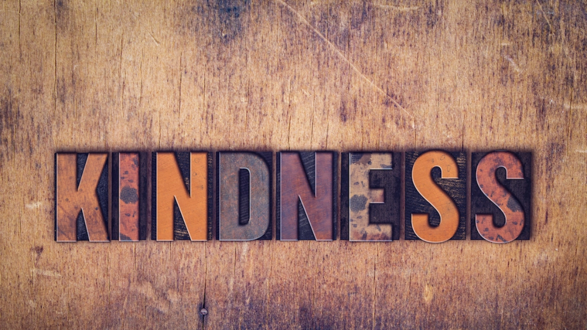 lettered blocks on a wood-grained surface spelling out the word "kindness"