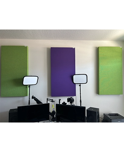 Image of a home office content creation studio with acoustic panels, lights, computer screens, a camera, and mic setup.